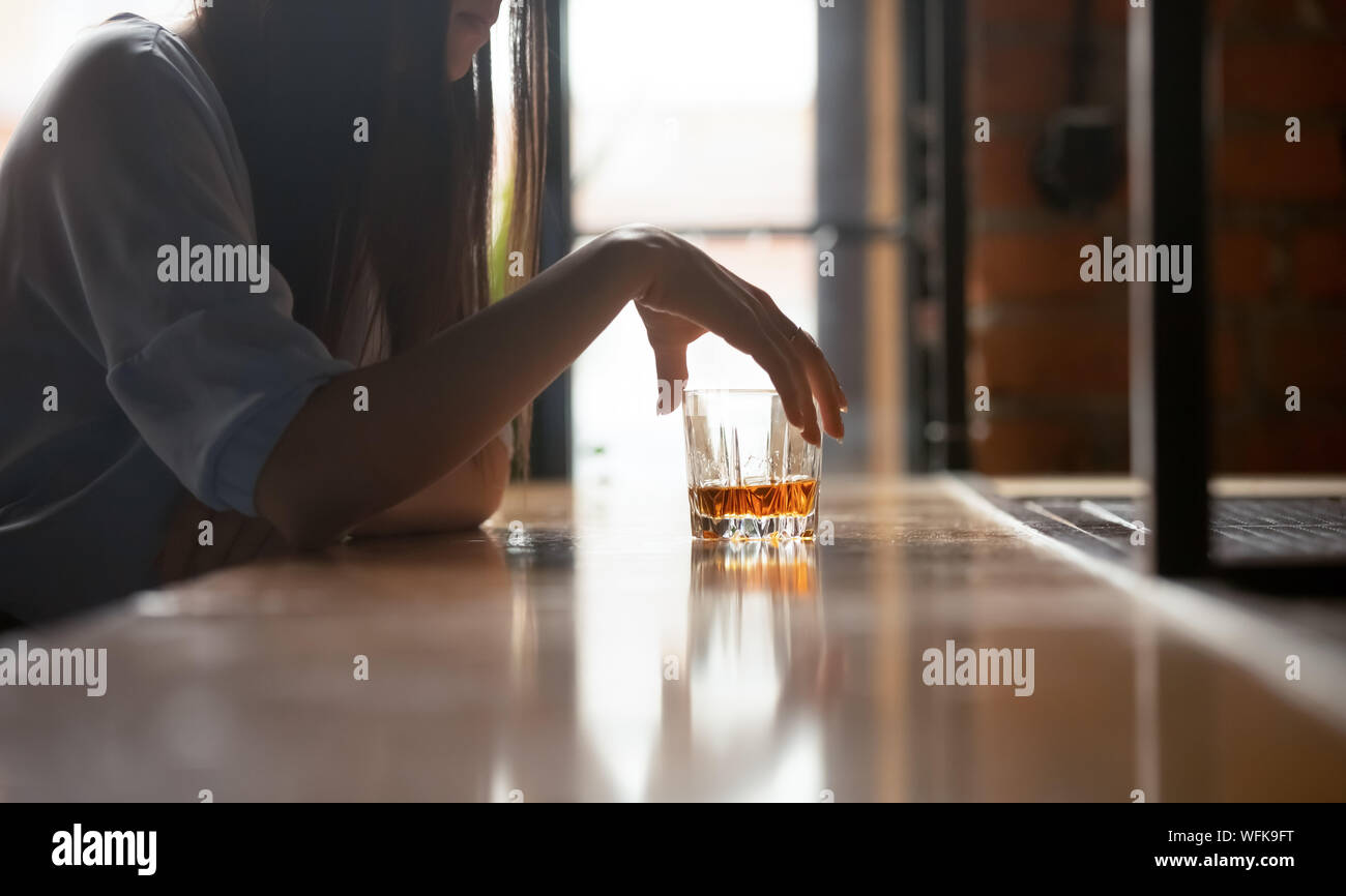 Sad woman drinker holding whiskey glass drinking alone in bar Stock Photo