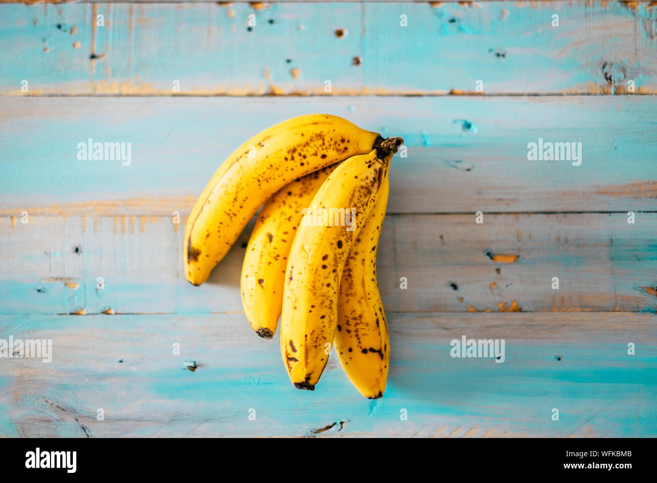 closeup of yellow and marron bananas on a blue table of wood diet and