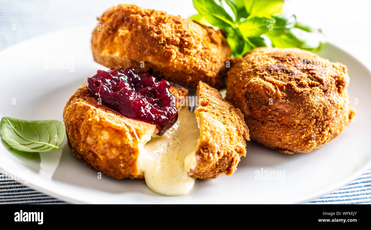 Fried camembert or brie cheese with cranberry jam and basil Stock Photo