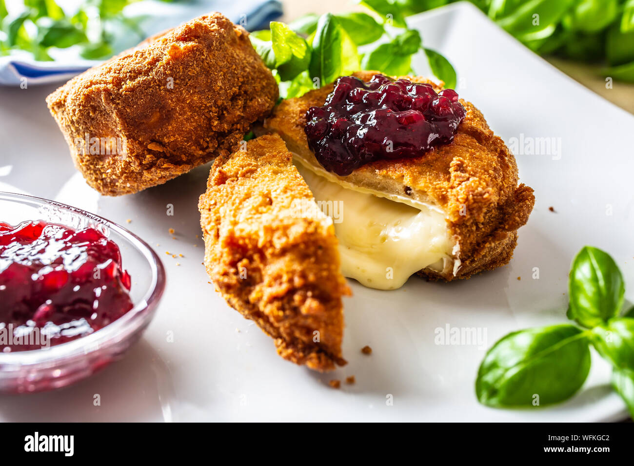 Fried camembert or brie cheese with cranberry jam and basil Stock Photo