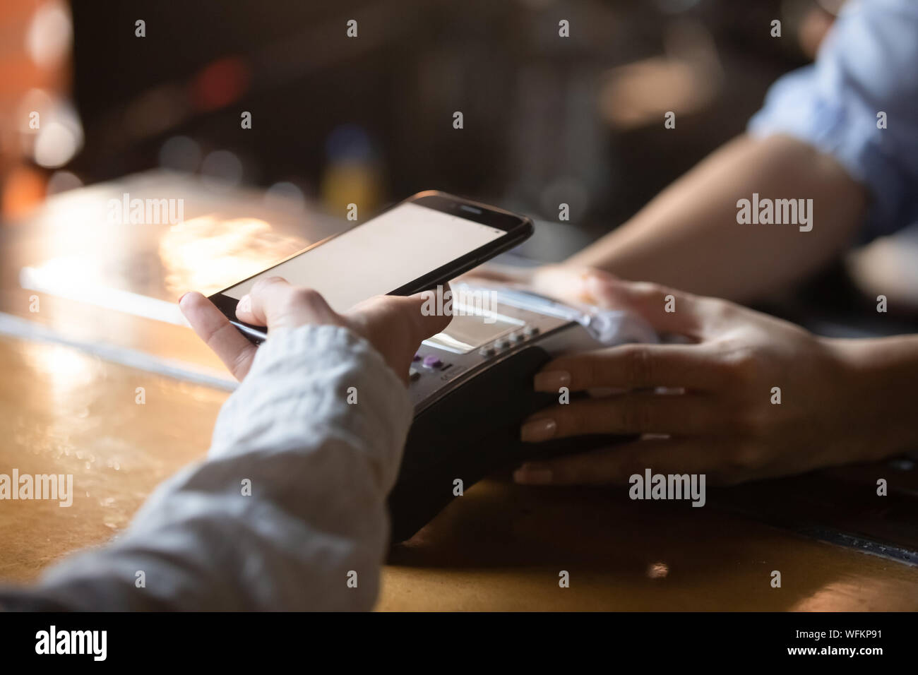 Woman customer holding phone near nfc terminal make mobile payment