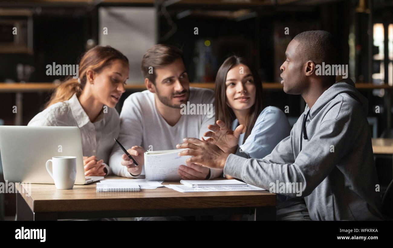 Focused african student talking to mates study together in cafe Stock Photo