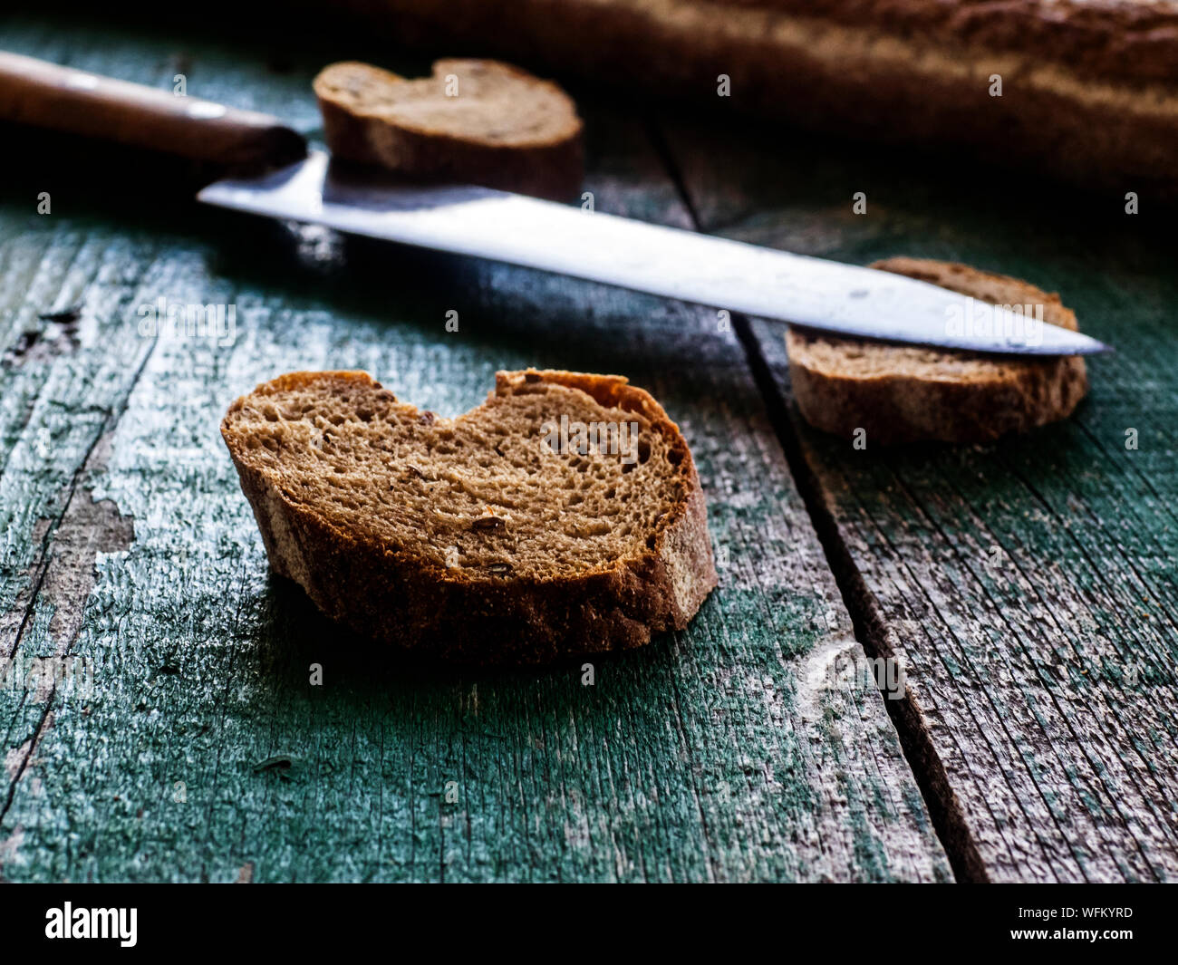 Bread Slices And Knife On Old Green Table Stock Photo