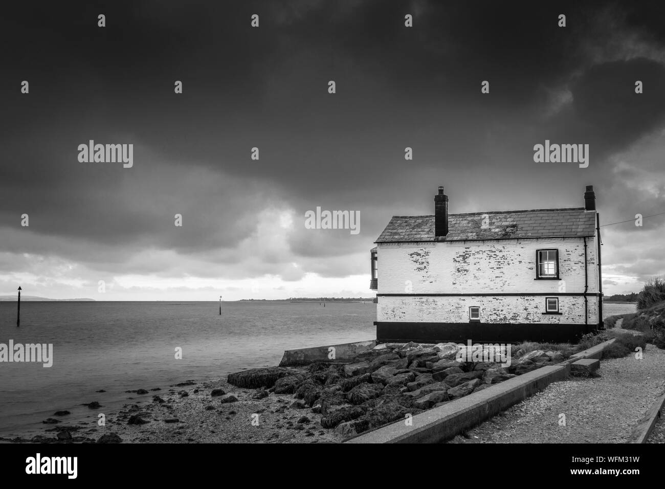 Monochrome of the historic Watch House at Lepe beach along the Solent in Hampshire with dramatic clouds scenery, England, UK Stock Photo