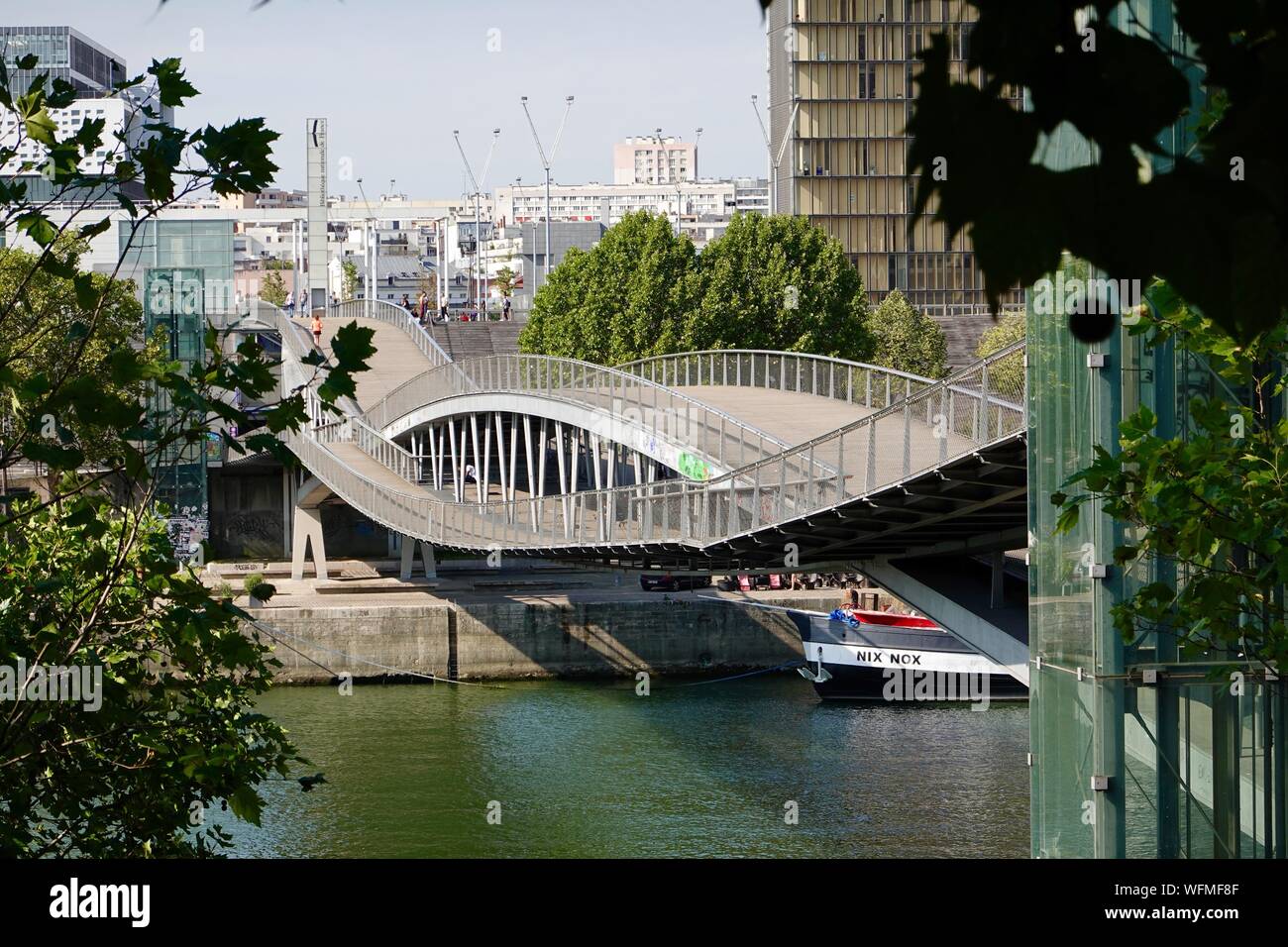 People on the Passerelle Simone-de-Beauvoir pedestrian bridge across the Seine River, looking south towards the library, Paris, France. Stock Photo