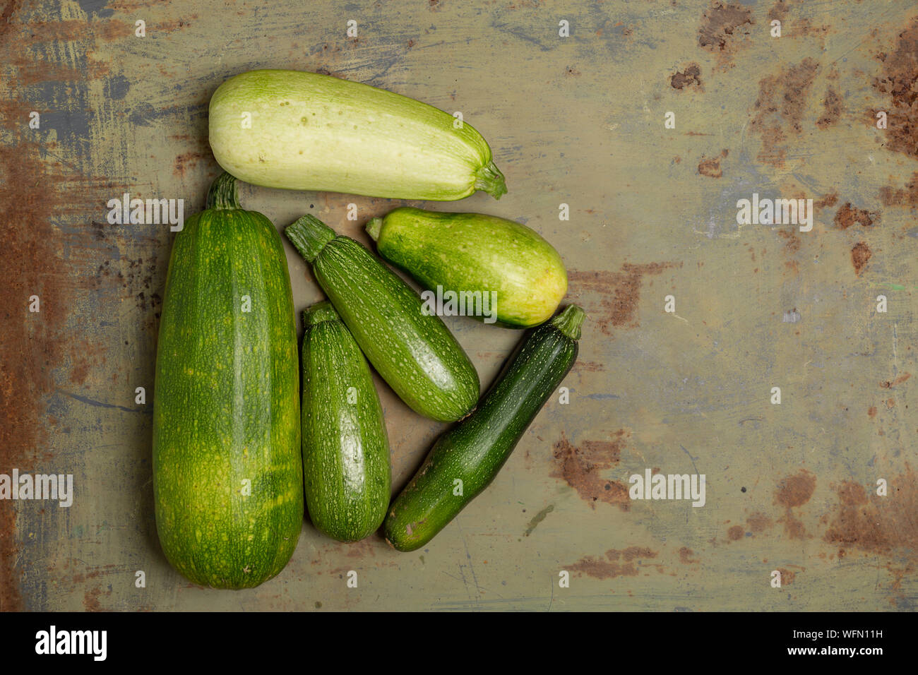 Fresh organic zucchini or green courgette on old metal surface. Top ...