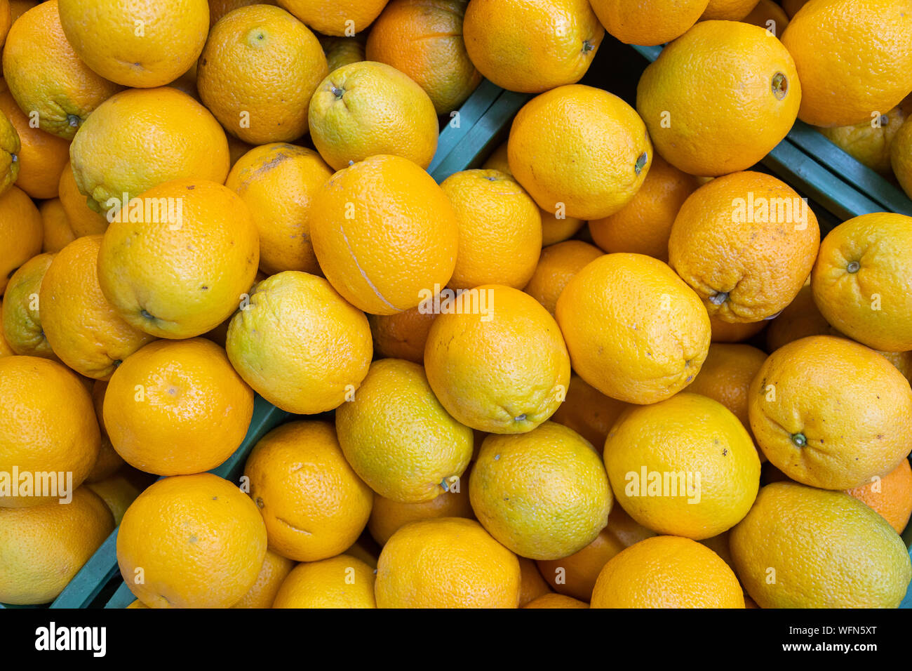Bright yellow oranges in wooden boxes at farmer's market or grocery