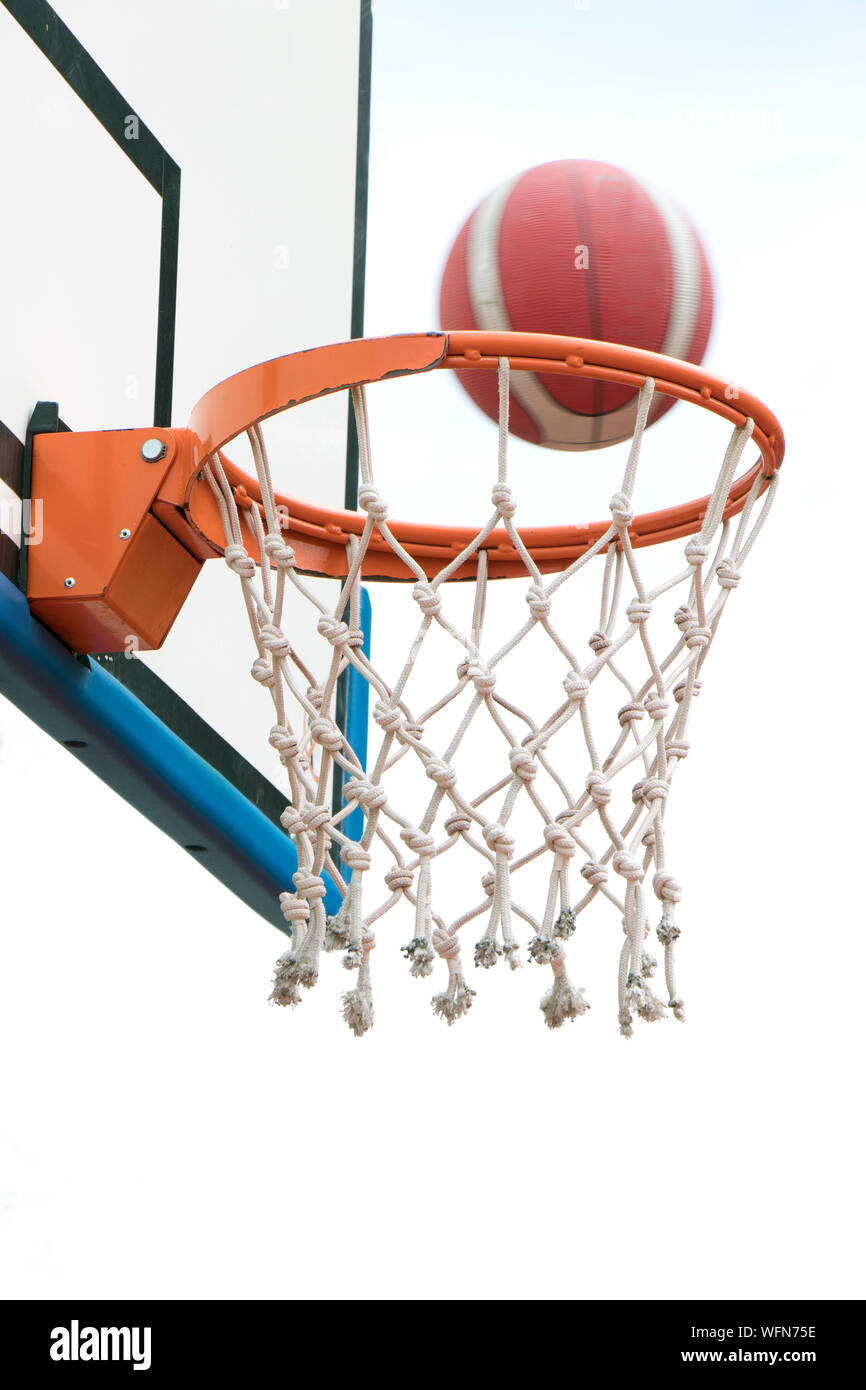 Basketball victory, a ball going through basket ring and net in motion blur. a successful clear point in low angle view, detail Stock Photo