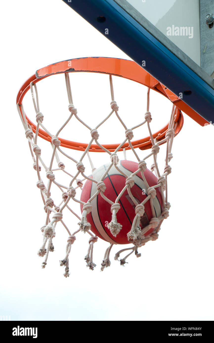 Basketball victory, a ball in a basket ring and net in motion blur, a successful clear point in low angle view, detail Stock Photo