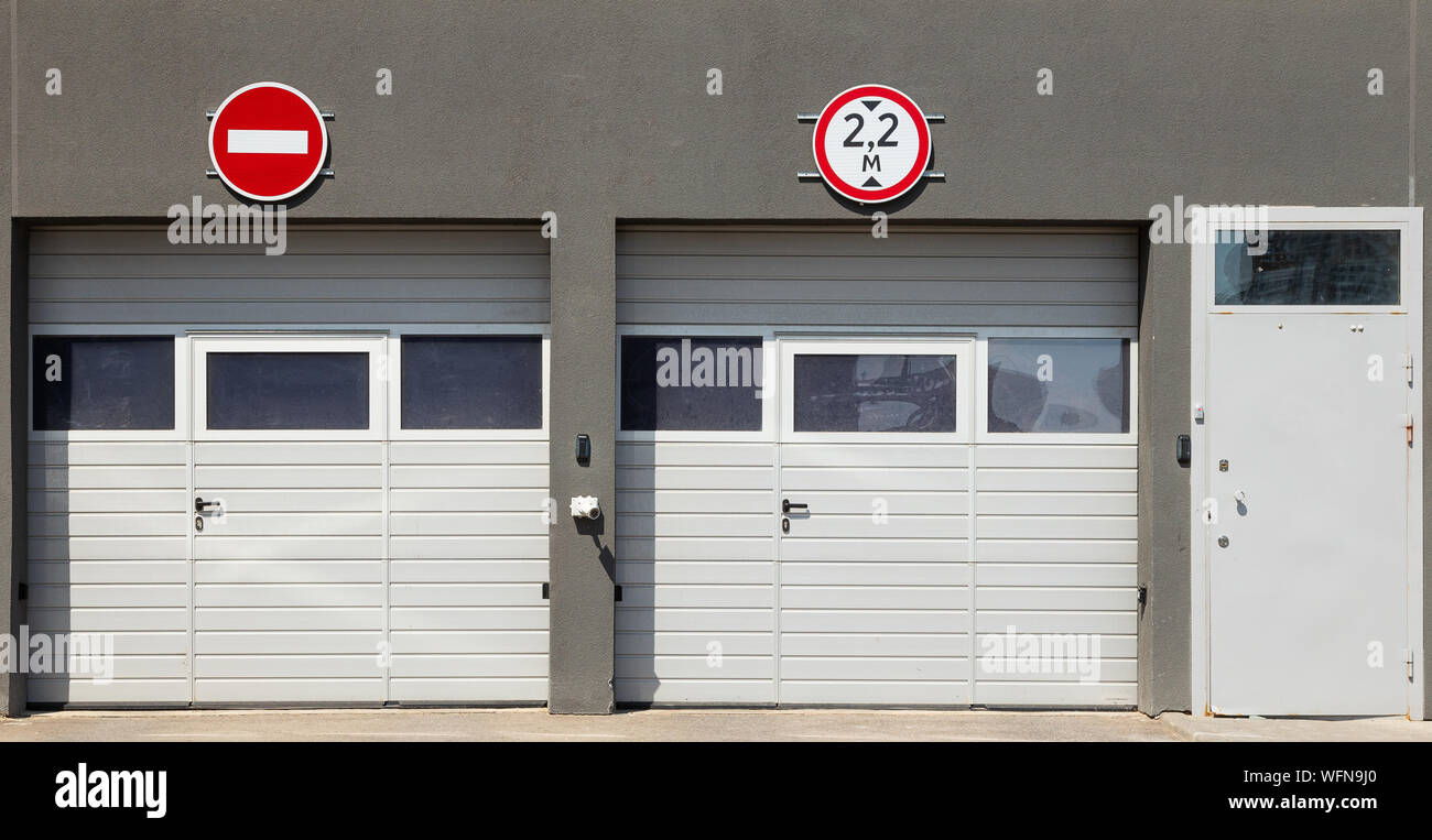 Front view at two closed white garage gates and one entry door, gray ...