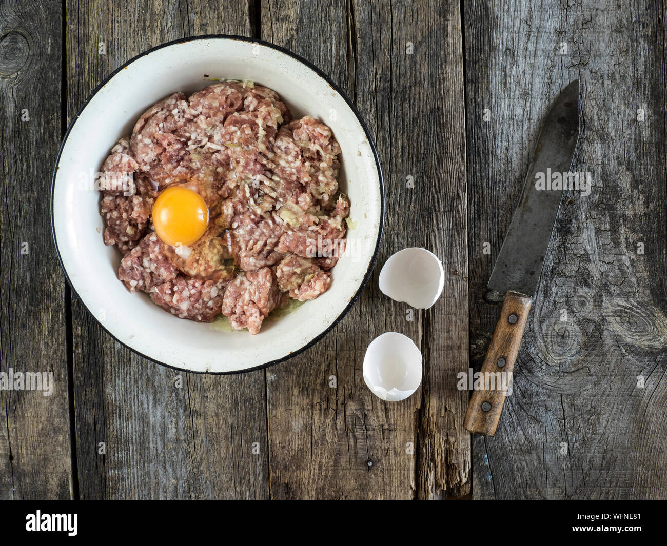 Directly Above View Of Egg Yolk With Raw Meat In Bowl By Eggshell And Knife On Wooden Table Stock Photo