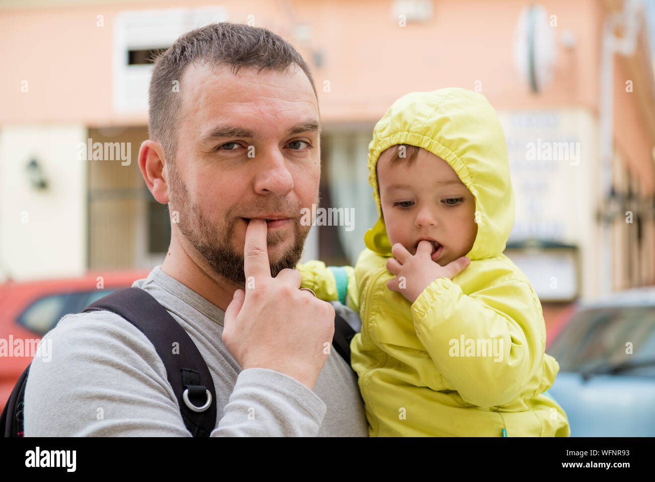 Portrait Of Father And Daughter Putting Fingers In Mouths Stock Photo