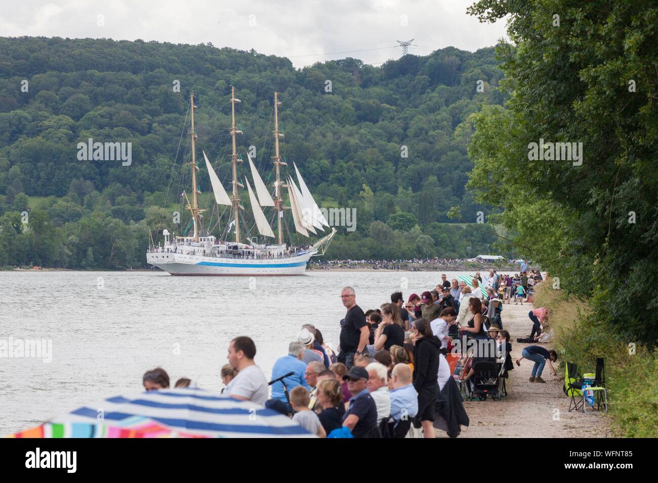 France, Seine Maritime, Mesnil sous Jumieges, Armada 2019, Grande Parade, crowd of spectators watching the Mir, three masted square rigged ship, sailing on the Seine River, among a lush green landscape Stock Photo