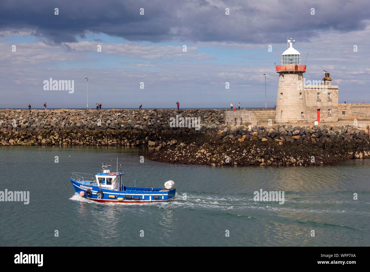 Ireland, Fingal County, northern suburbs of Dublin, Howth, the port, departure of a fishing boat passing in front of the lighthouse of the city Stock Photo