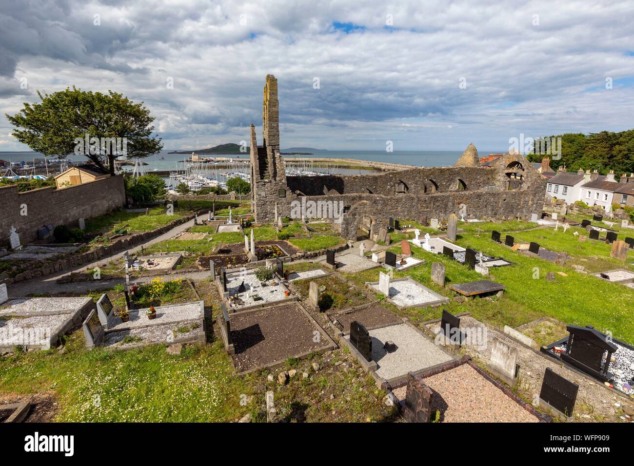 Ireland, County Fingal, Dublin's northern suburbs, Howth, former Saint Mary's church and cemetery, at the bottom the port and lighthouse of the city Stock Photo