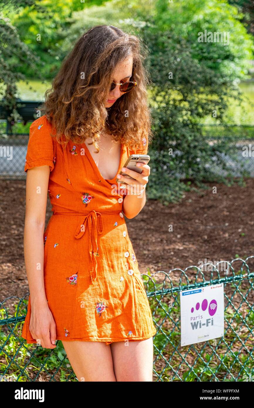 France, Paris, young woman using the free wifi network of parks and gardens Stock Photo