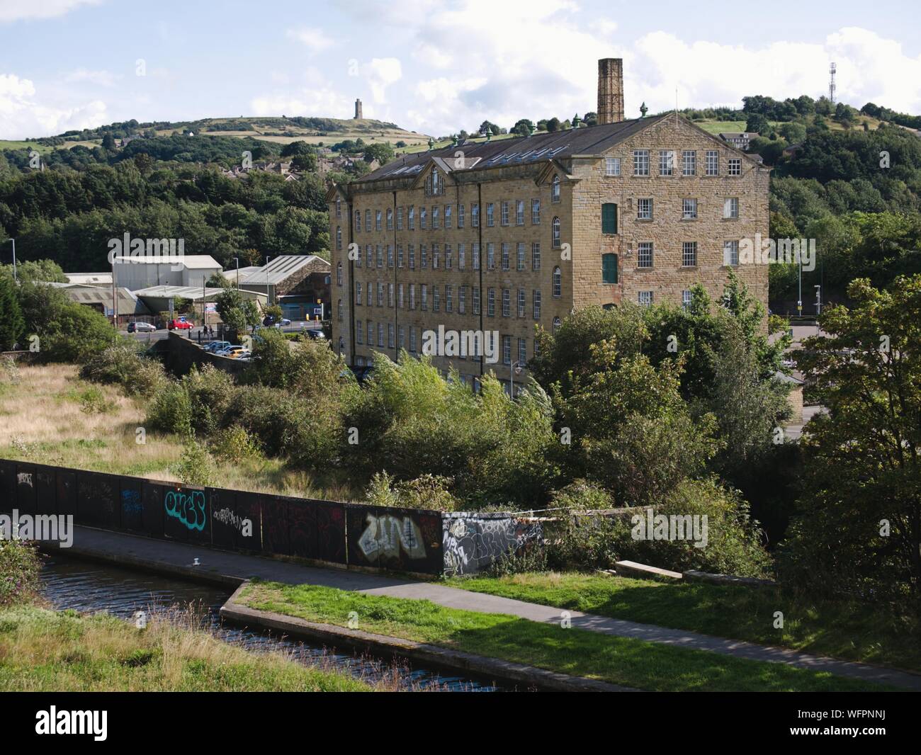 Rear of Folly Hall mill looking across the huddersfield narrow canal and river ex Joseph Lumb now used by the NHS Stock Photo