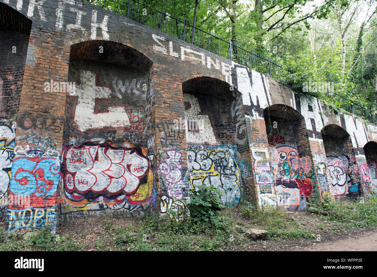 Graffiti on brick embankment, Parkland Walk, a disused railway line now an urban nature reserve, London Borough of Islington Stock Photo