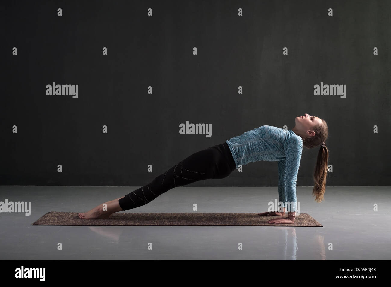 Woman practices yoga asana purvottanasana or upward facing plank full pose isolated on black background Stock Photo