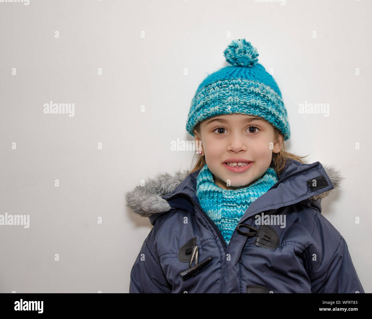 Portrait Of Smiling Girl Wearing Warm Clothing Against White Background
