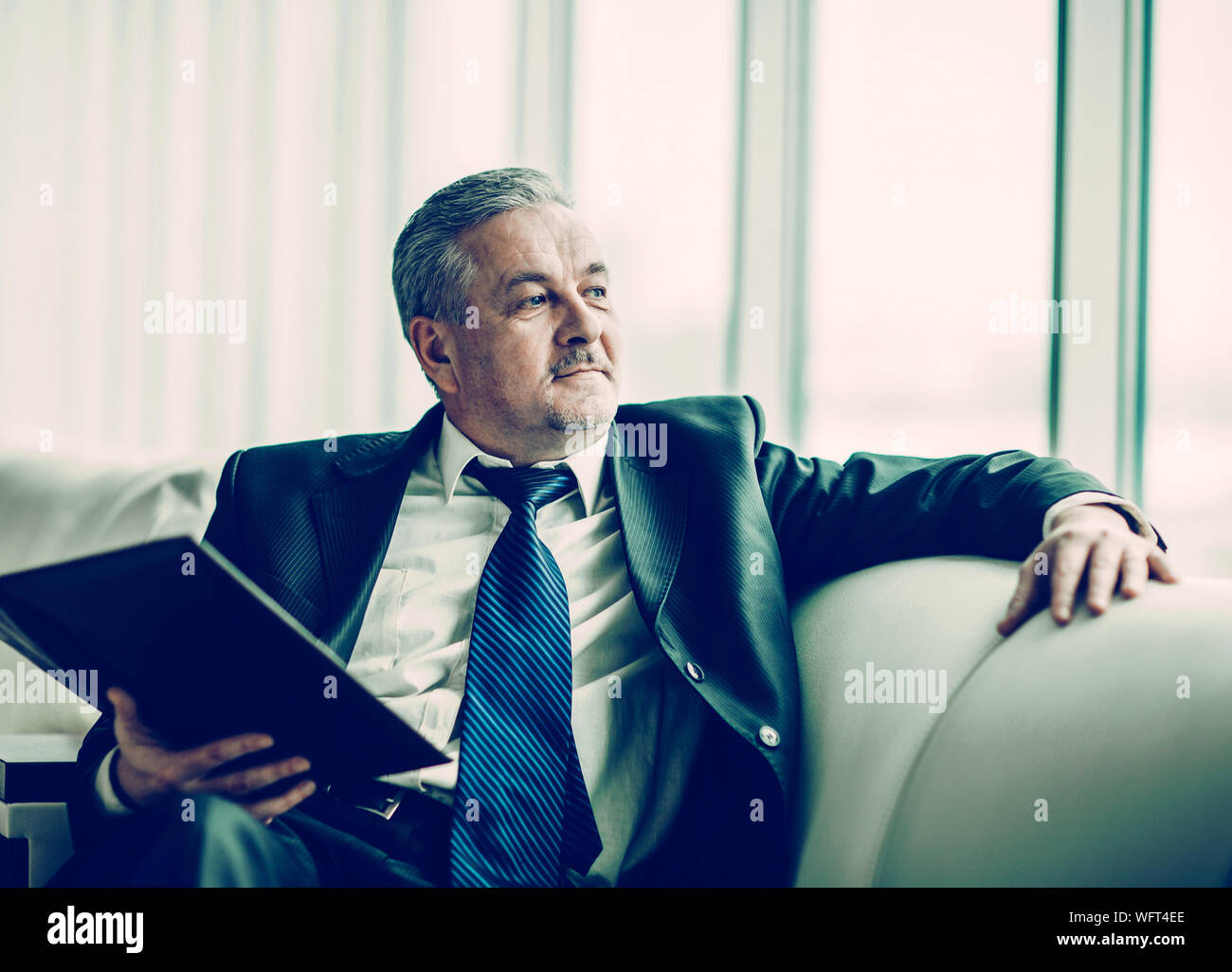 successful businessman with business documents sitting on a sofa in a private office Stock Photo