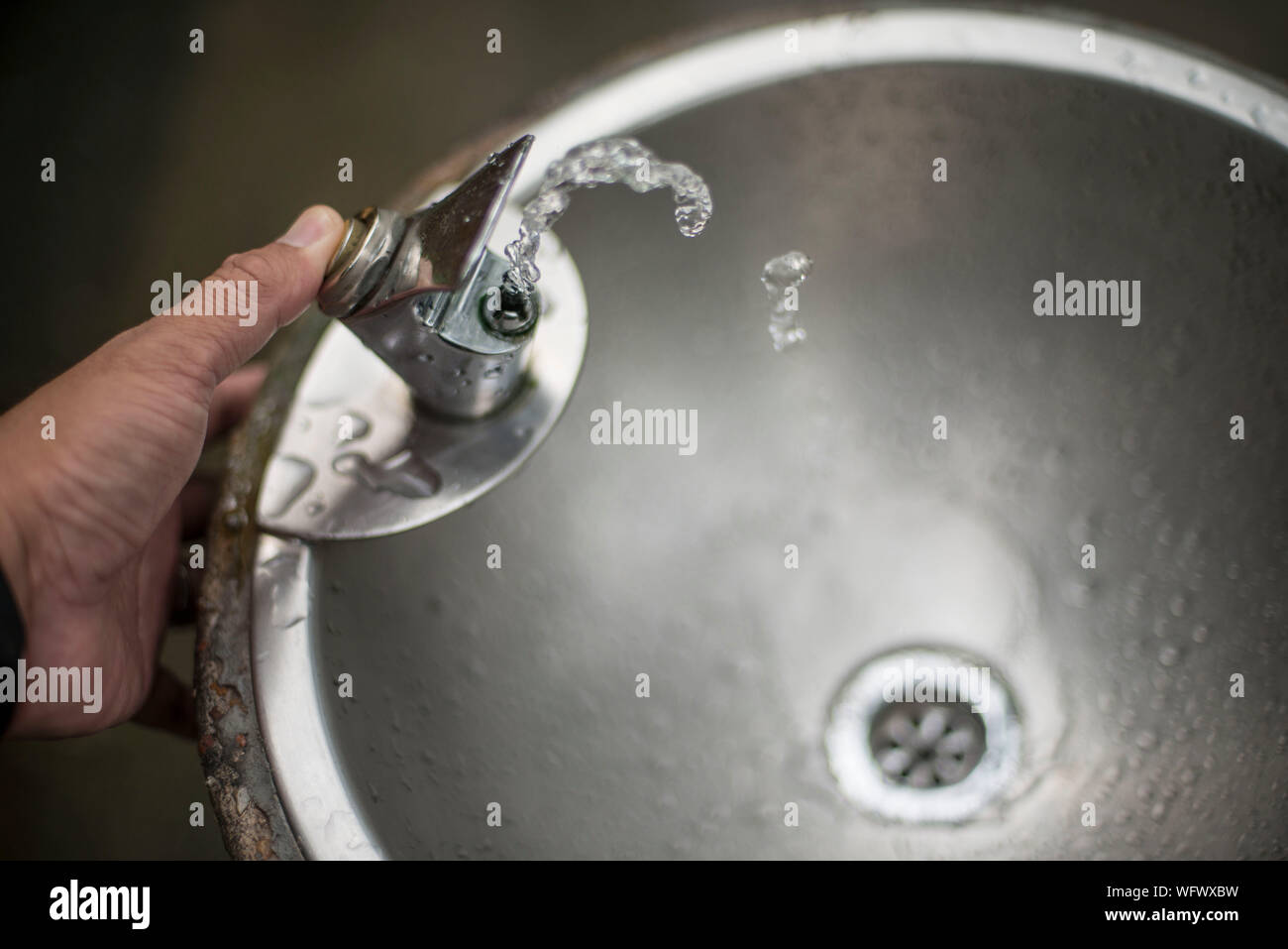 Cropped Hand Pressing Faucet Button Of Drinking Fountain Stock Photo