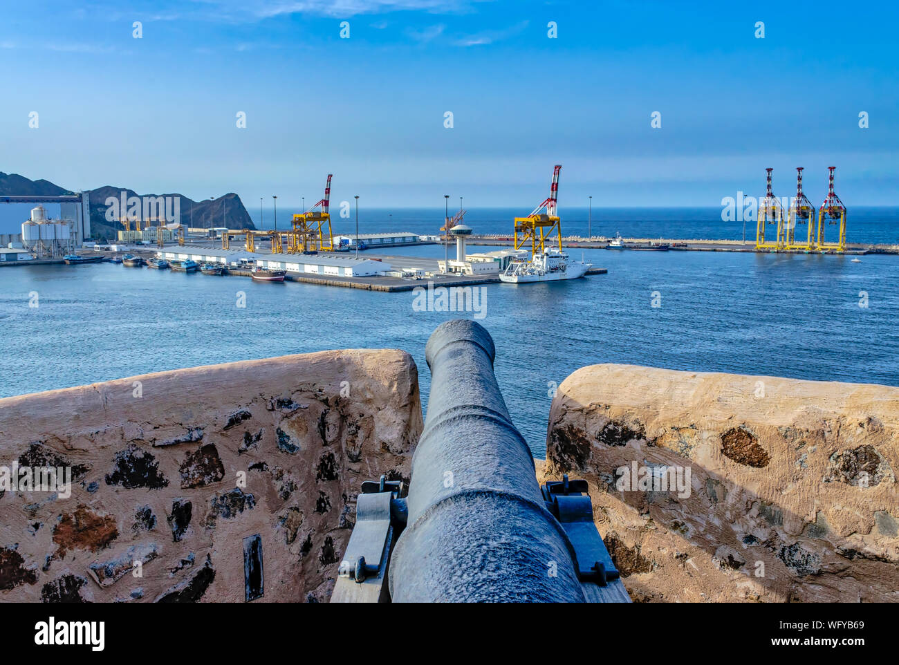 Old cannon on the fort watch tower pointing towards the port and the sea with blue sky background. From Muscat, oman. Stock Photo