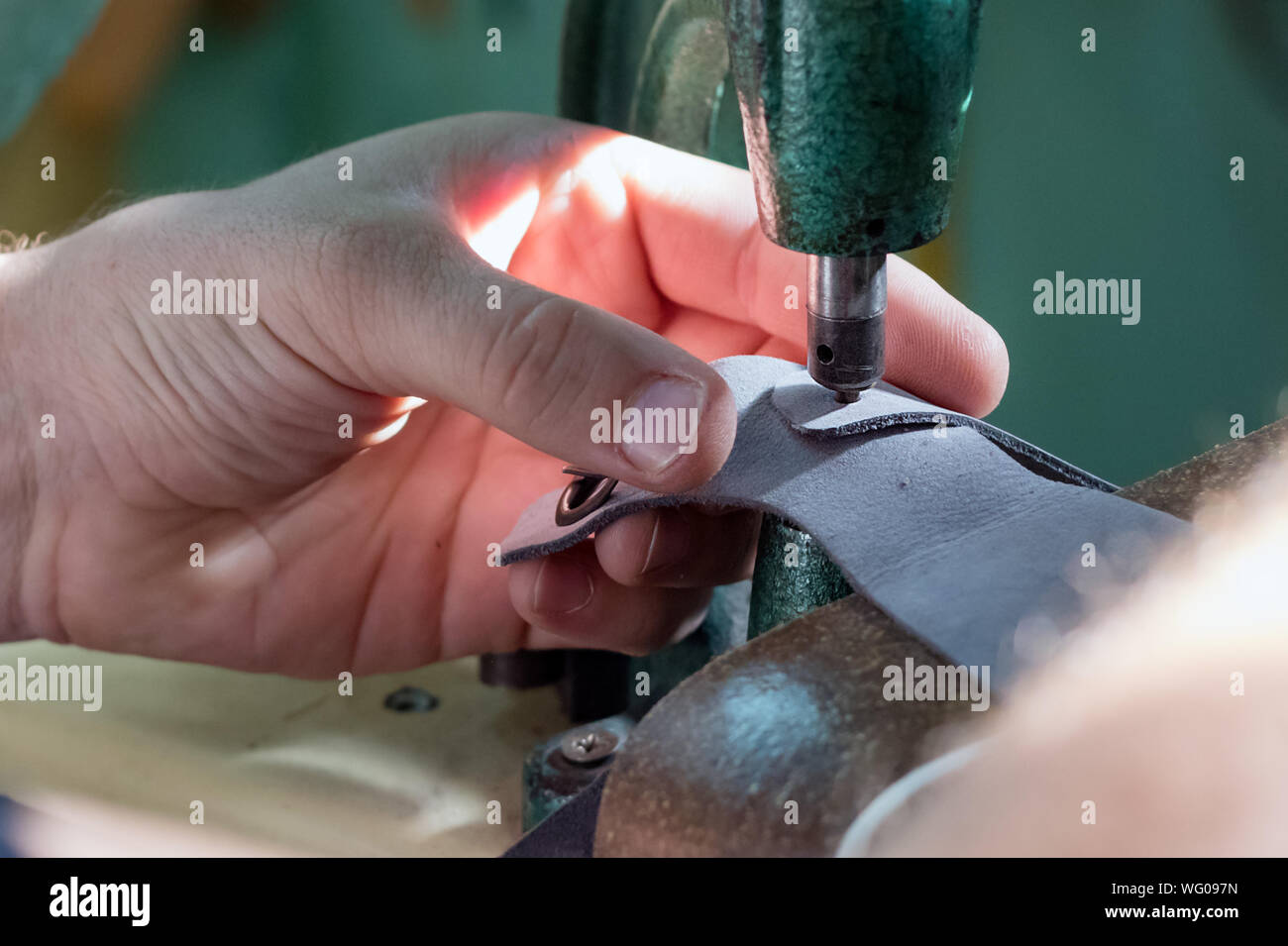 Close up of the hands of a male shoemaker riveting with an old rivet press machine. Stock Photo