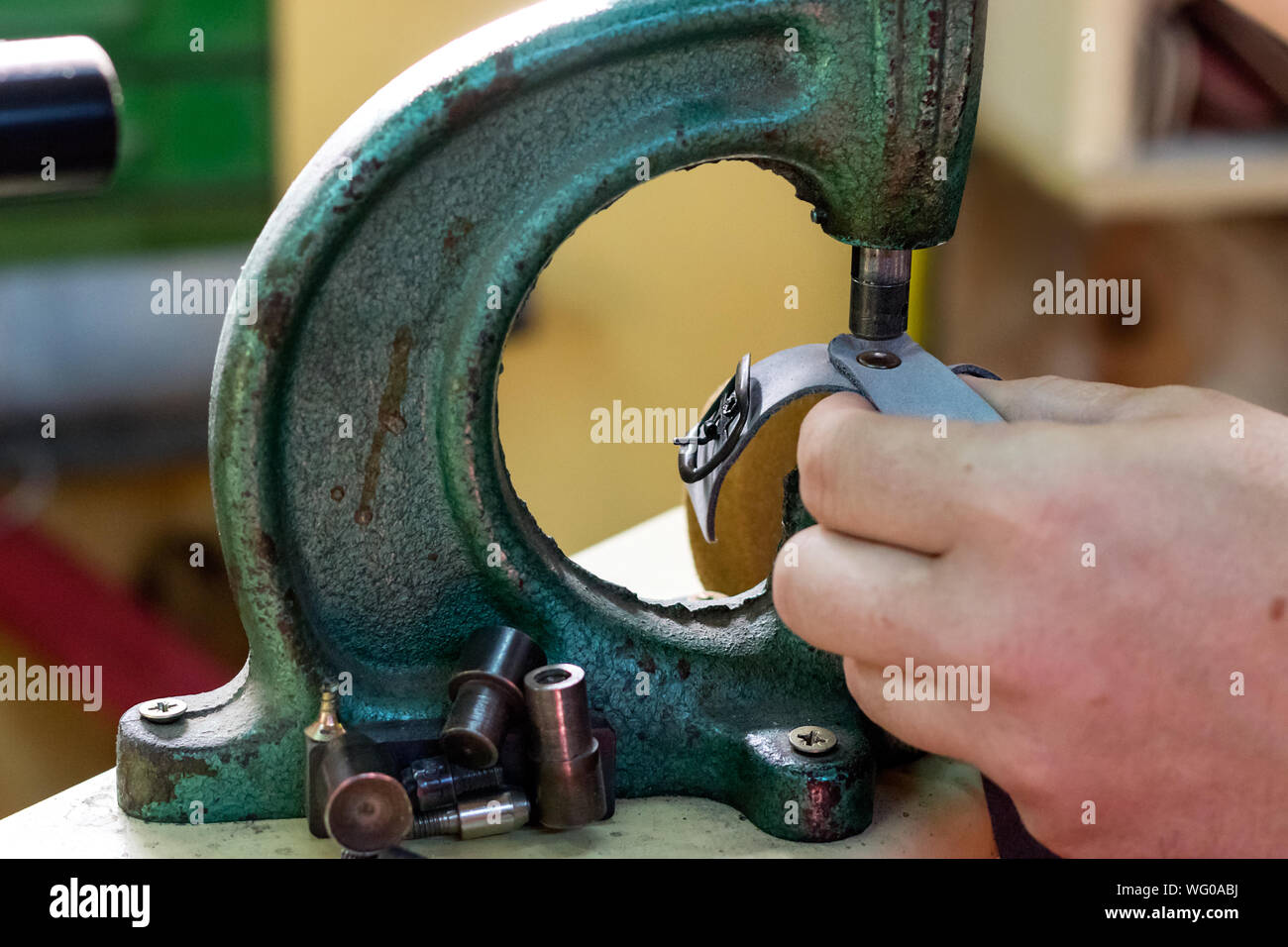 Close up of the hands of a male shoemaker placing a double cap rivet