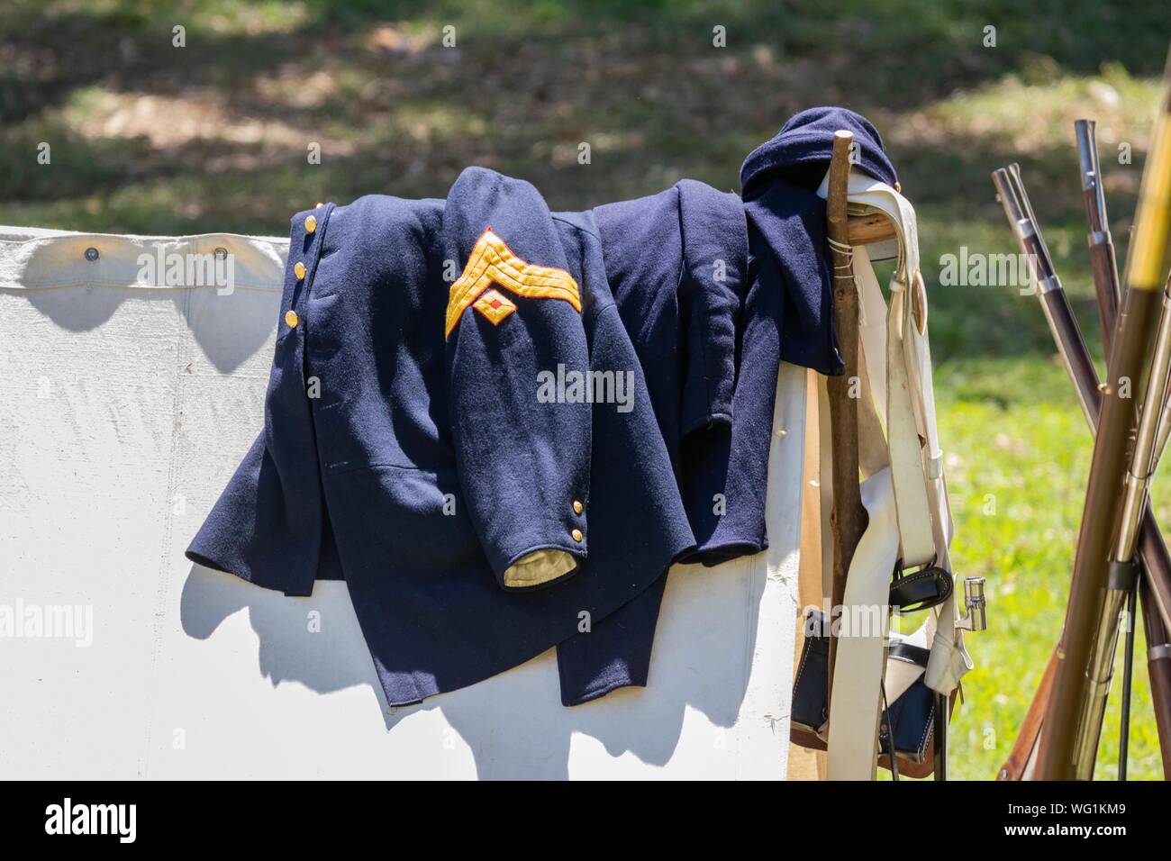 Union army jacket and gear lay on a white canvas tent during an American Civil War Reenactment Stock Photo
