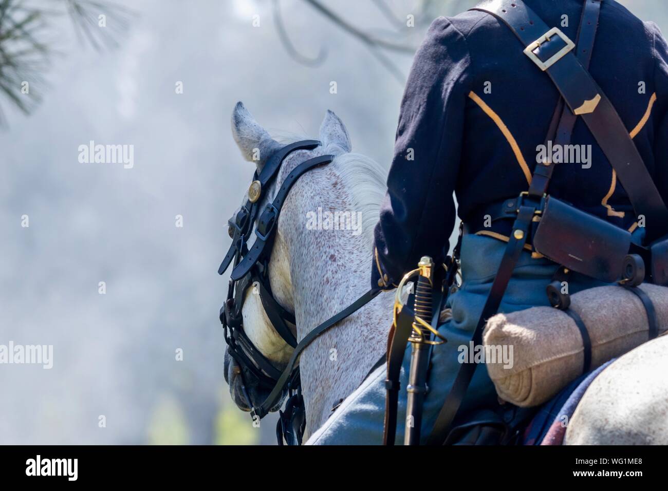 A man dressed as a union general riding a white horse into a cannon smoke covered battlefield