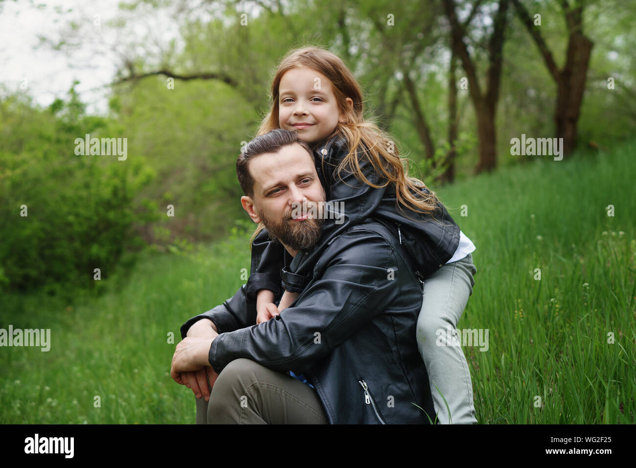 Fashionable happy family walking in the park. Portrait of a loving daughter and a caring father. Time together. Family look. Urban casual outfit. Stock Photo