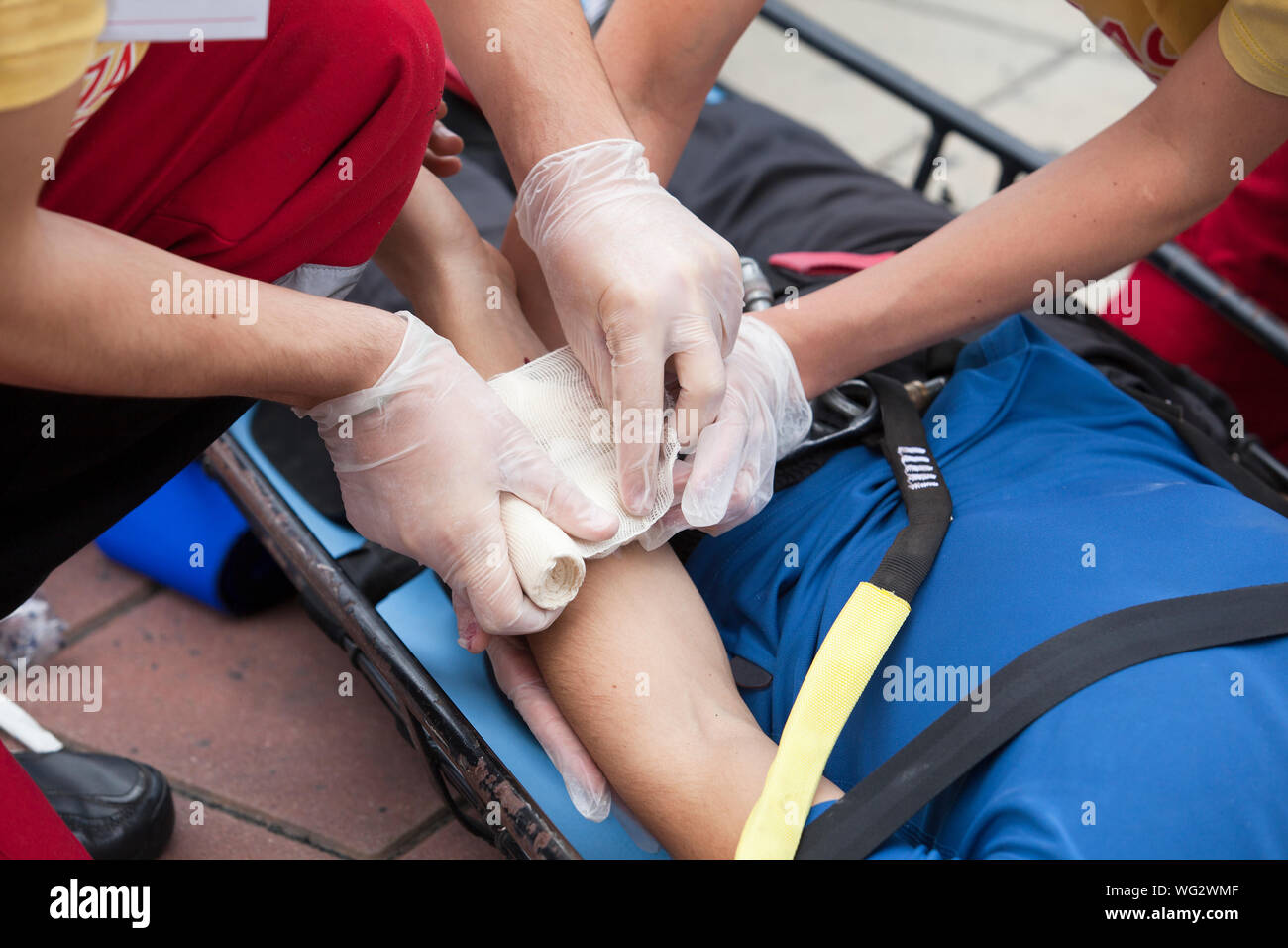 Midsection Of Healthcare Workers Bandaging Patient On Stretcher Stock Photo
