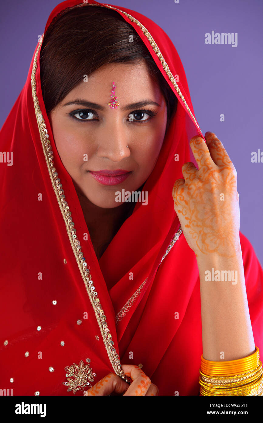 Portrait Of Beautiful Indian Woman In Red Sari Against Purple Background Stock Photo