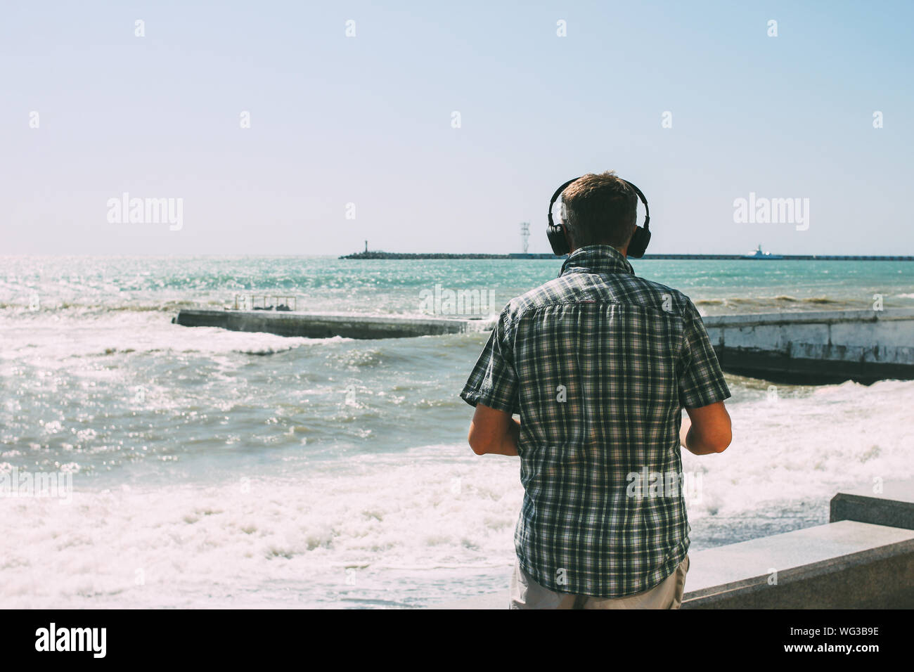 Adult man with headphones looking at the stormy sea Stock Photo