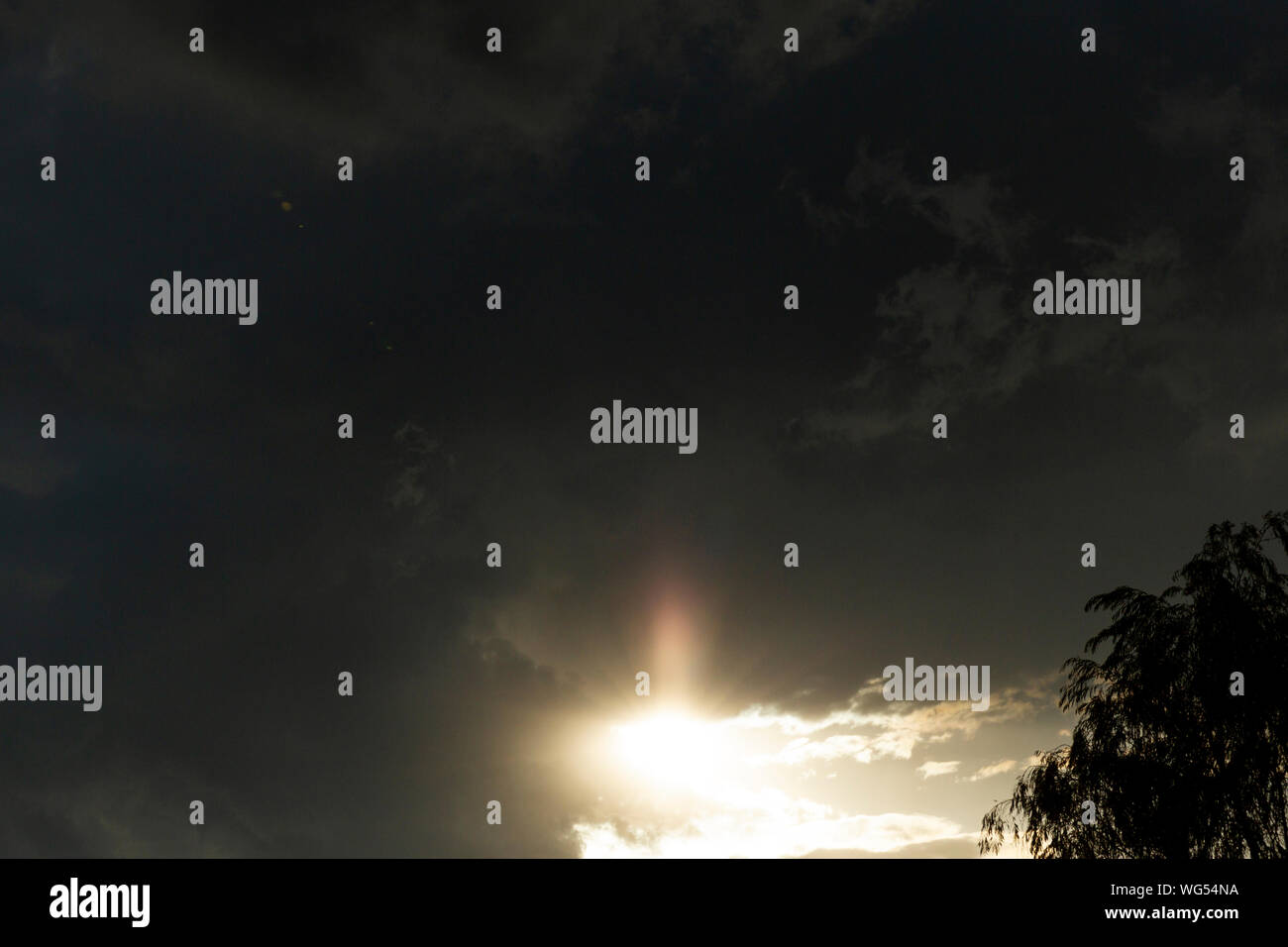 Sunshine peaking out from behind very dark cloud passing Stock Photo ...