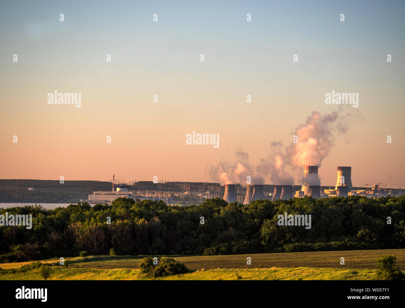 Cooling Towers At Nuclear Power Station Against Sky During Sunset Stock Photo