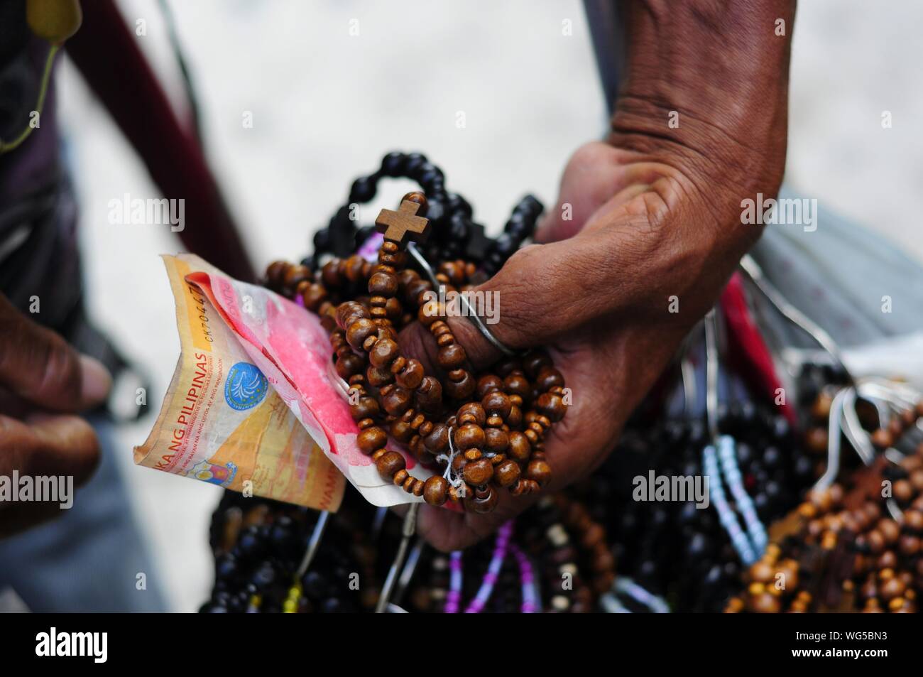 Close-up Of Vendor With Money And Rosaries Stock Photo