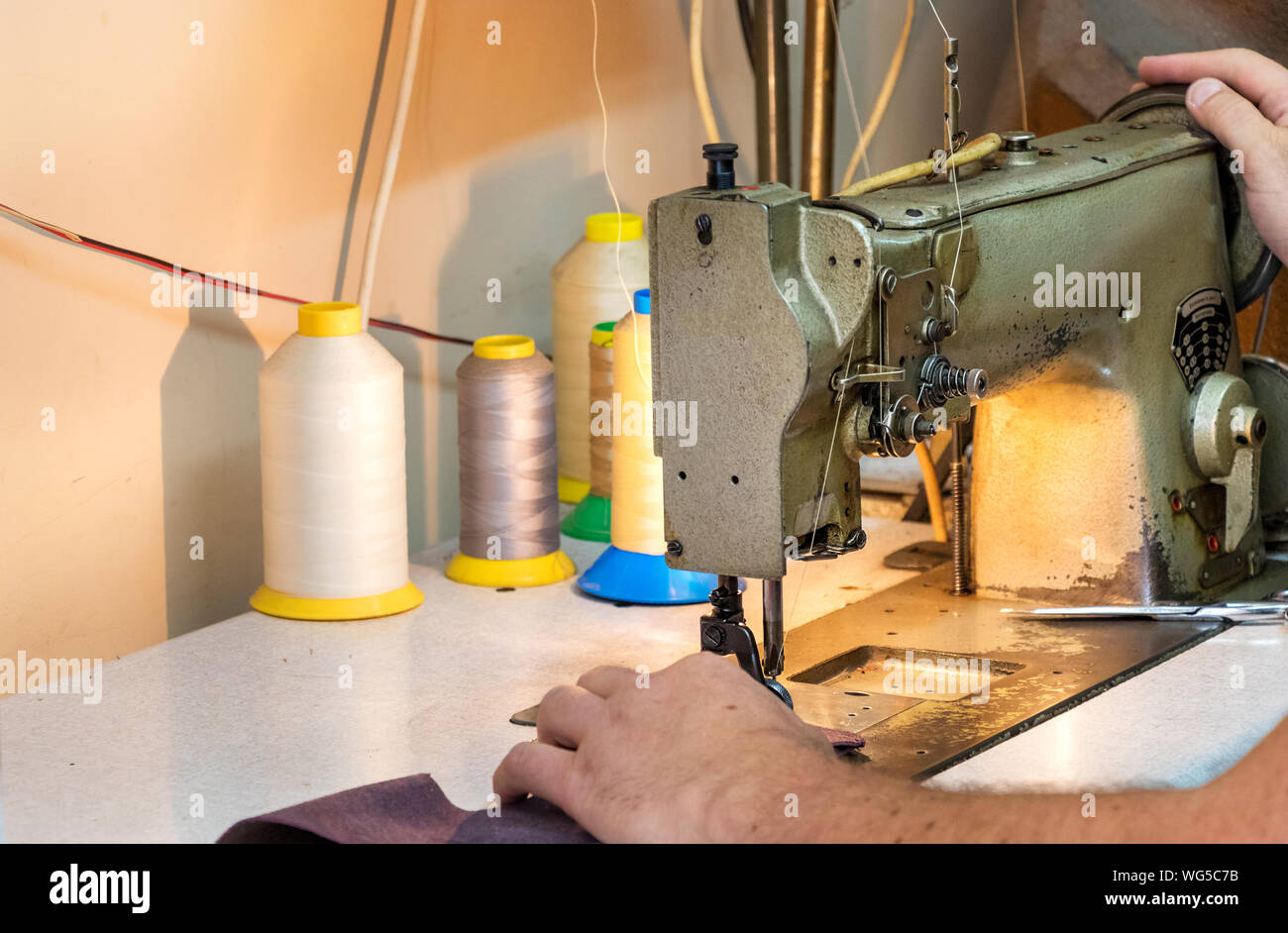 A male shoemaker hands, sewing leather with an old sewing machine Stock