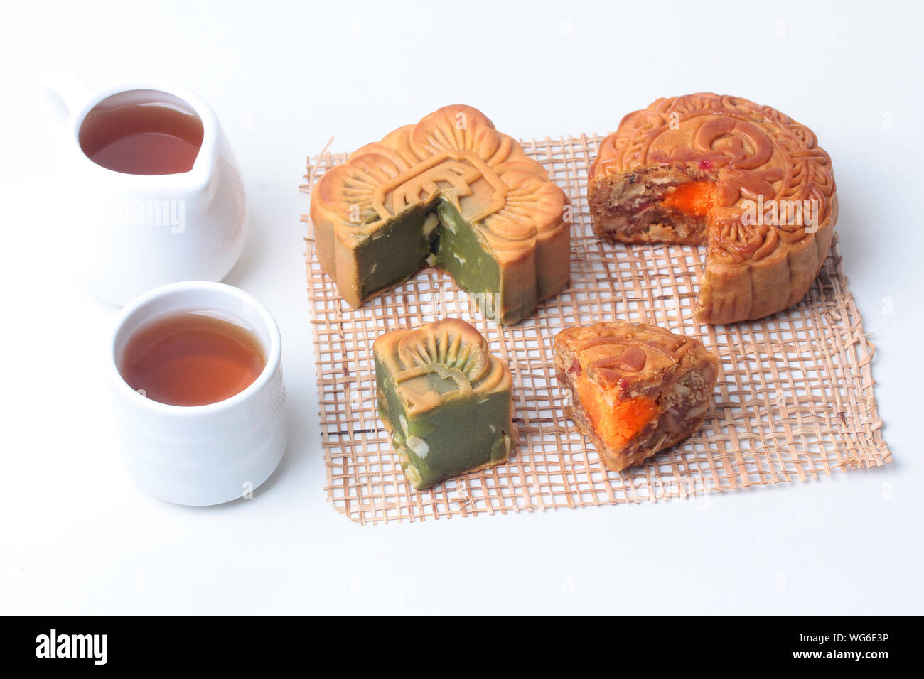 Round mooncake 8 grains and salted eggs and squred shaped moon cakes, red beans, stirred in green tea and chopped macadamia nuts served with tea and t Stock Photo