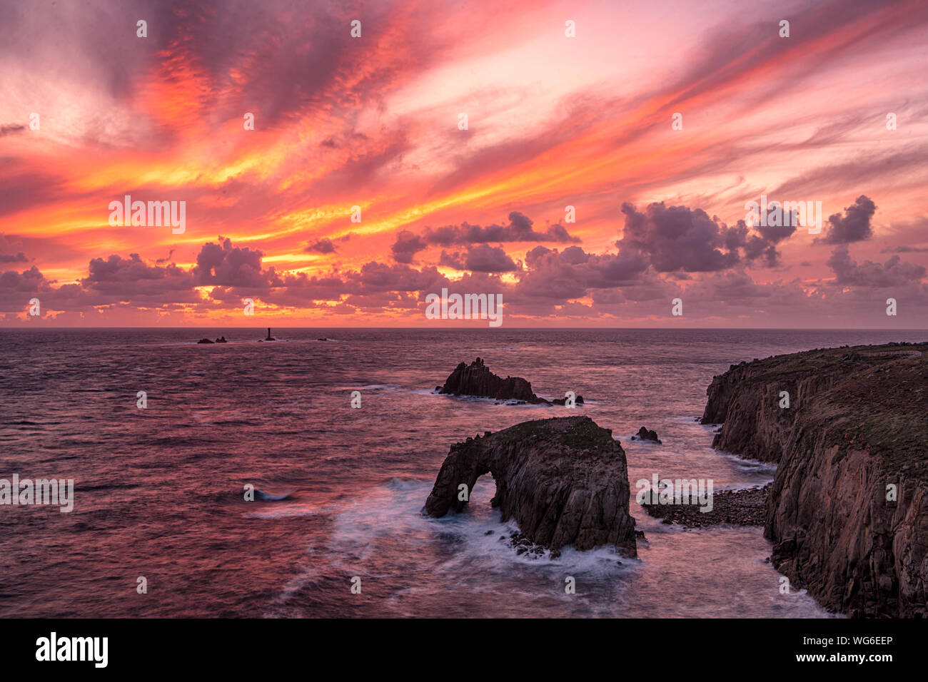 Lands End Cornwal Sunset set at Lands End Cornwall with Enys Dodnan Arch, and longship lighthouse,Lands End Cornwall on the Cornish Coastal Walk Stock Photo