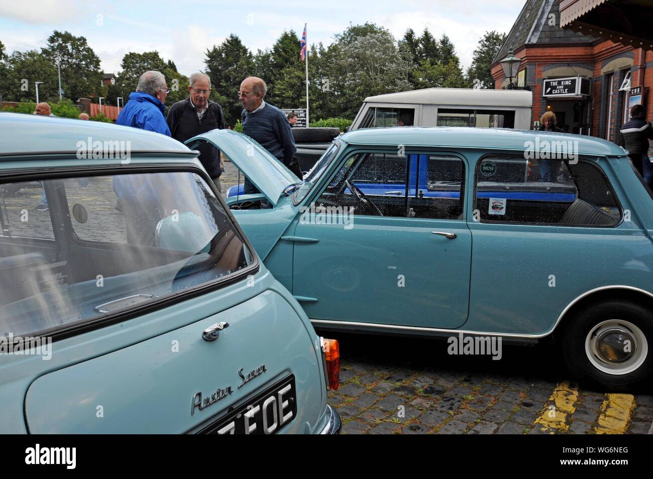 Car enthusiasts discussing a 1960 Austin Seven Mini on display at the