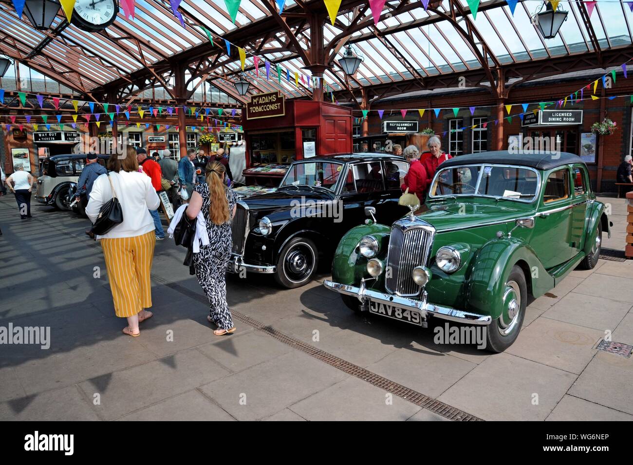 Visitors studying classic cars including a green 1953 Riley at the