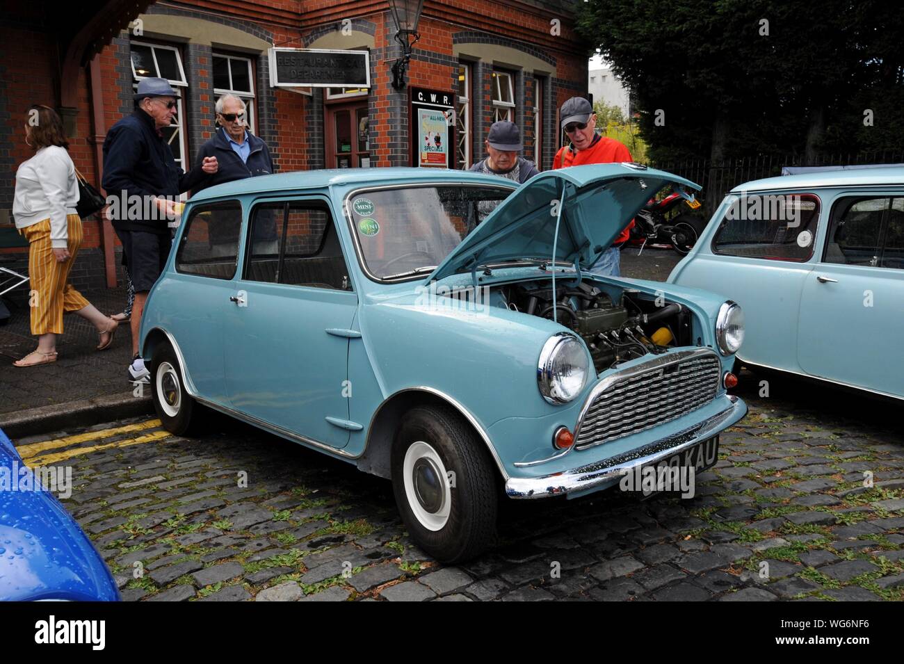Car enthusiasts discussing a 1960 Austin Seven Mini on display at the