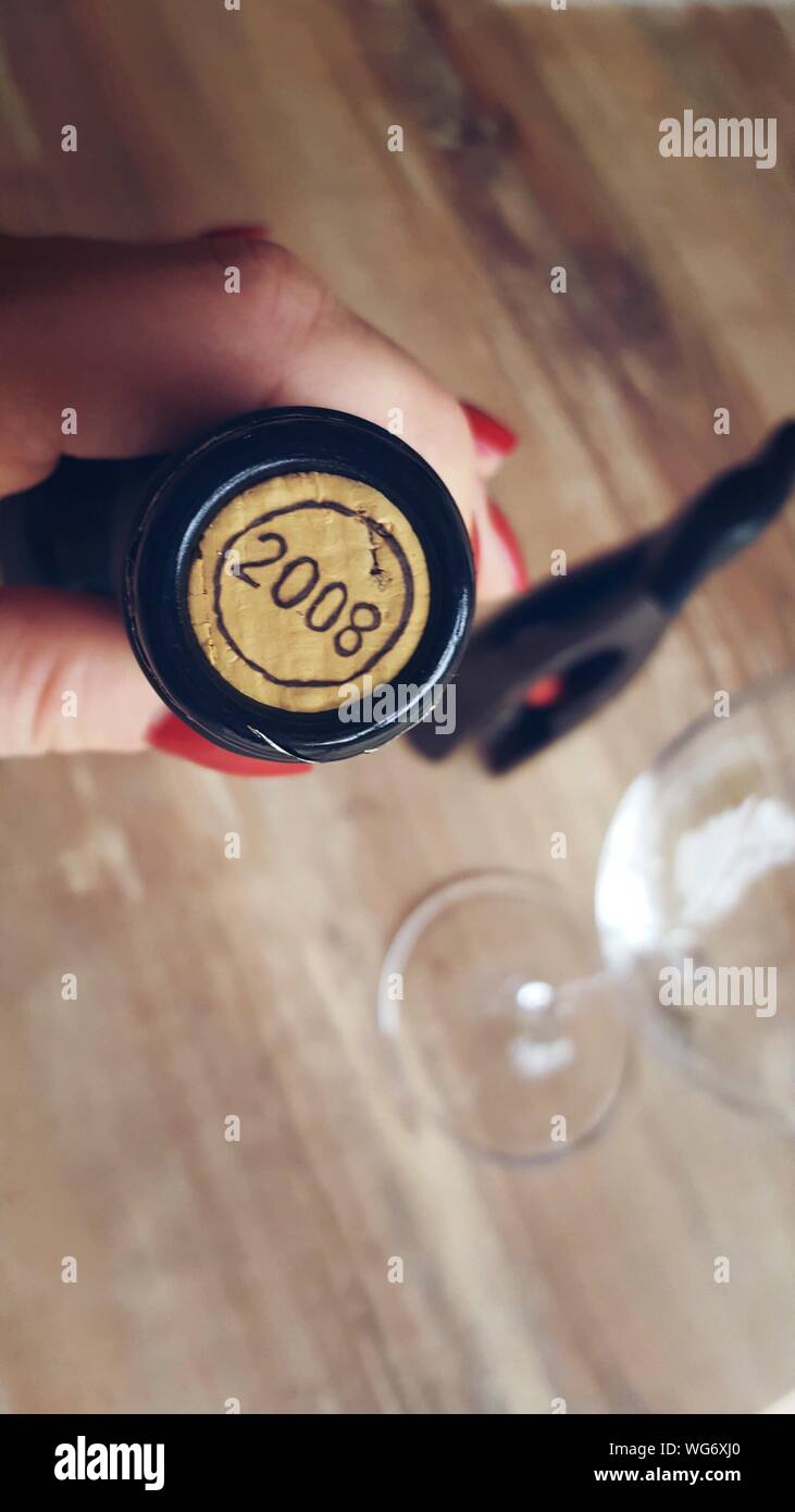 Cropped Hand Of Woman Holding Wine Bottle With Number On Cork Stock Photo