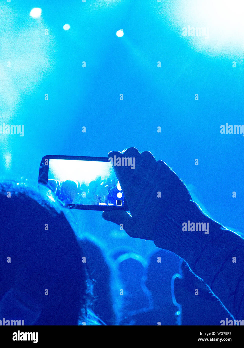 Concert crowd clapping in front of a bright stage Stock Photo Alamy