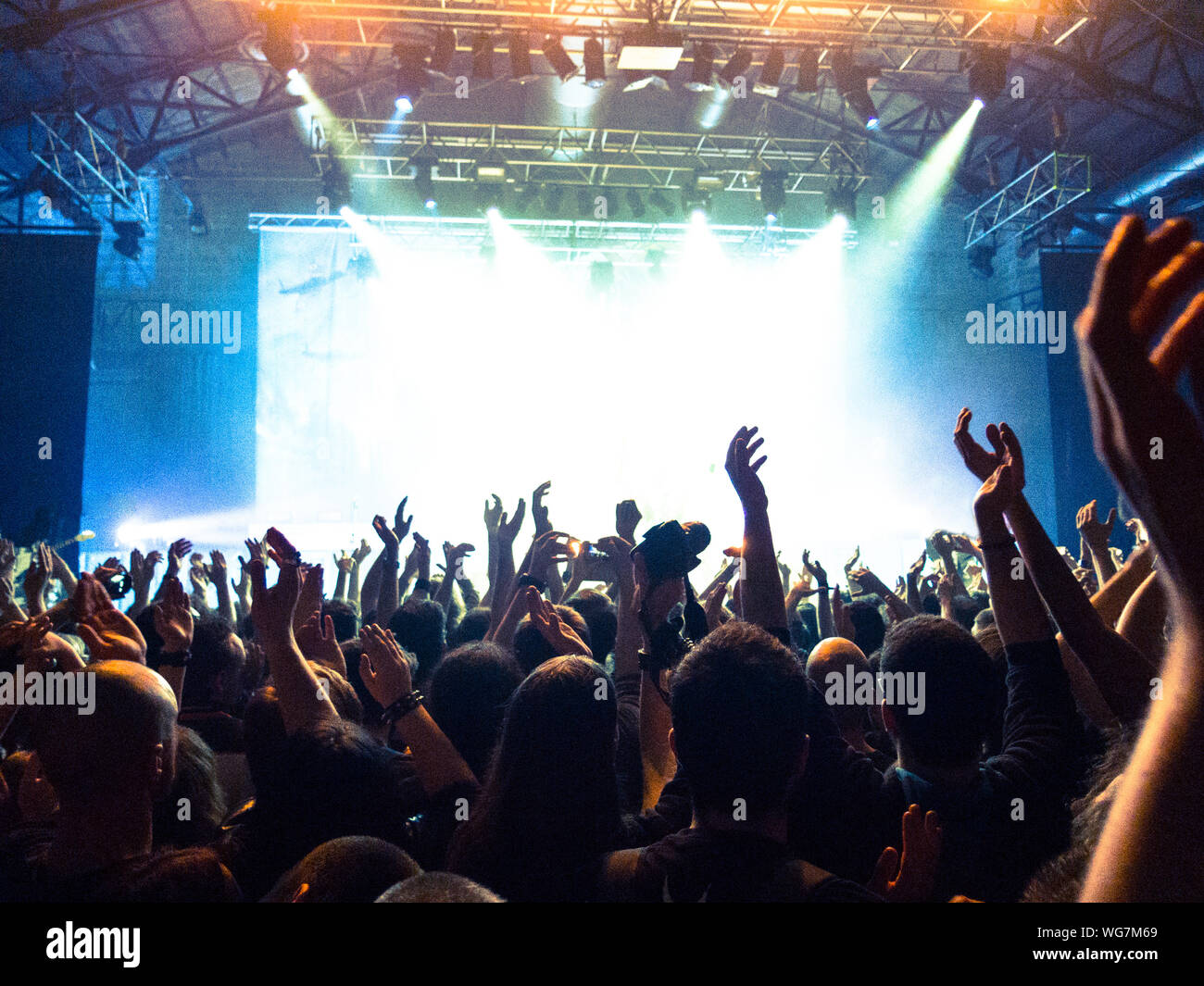 Concert crowd clapping in front of a bright stage Stock Photo - Alamy