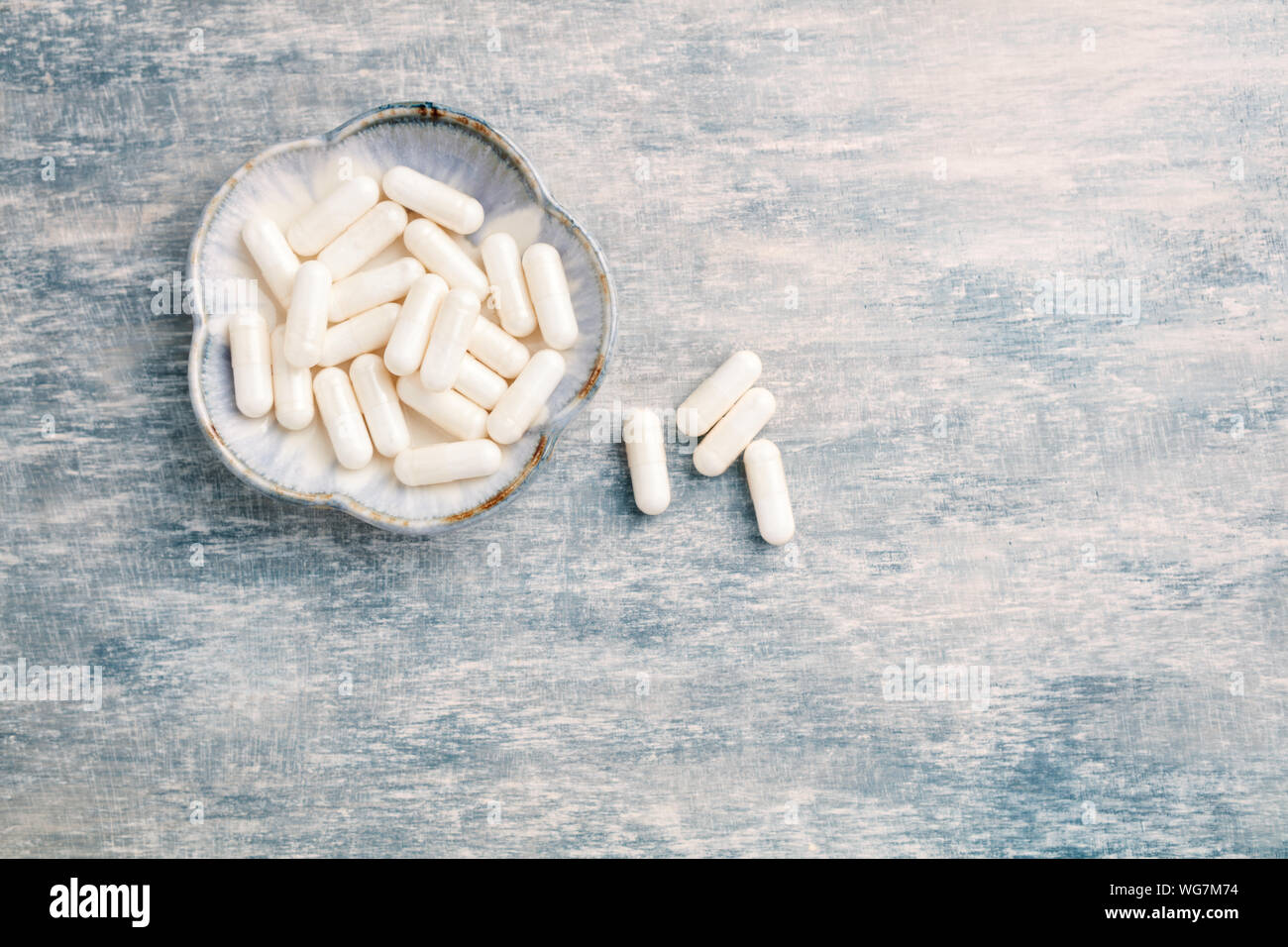 Glycine capsules. Concept for a healthy dietary supplementation. Nervous System Support. Bright wooden background. Top view. Copy space. Stock Photo