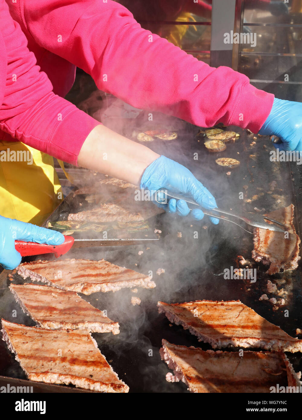 cook with latex gloves while cooking sausage on the hot plate of the