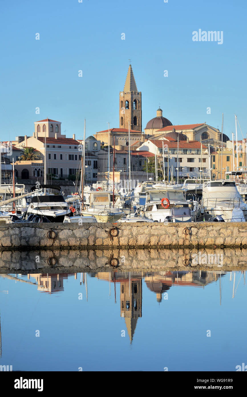 panoramic view of aAlghero with the bell tower of the cathedral in evidence and its reflection on the water of the harbor Stock Photo